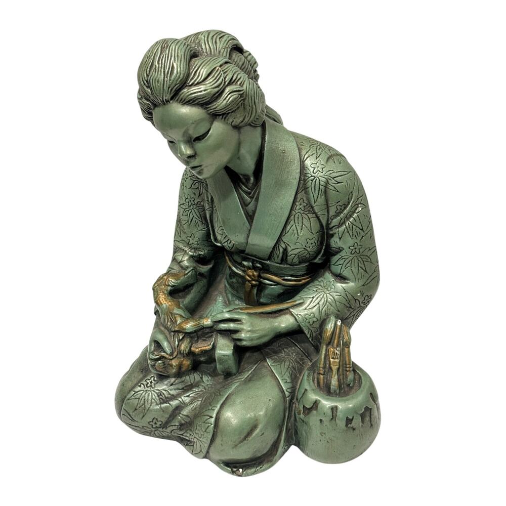 A Japanese woman geisha artist painting a small object using traditional brushes